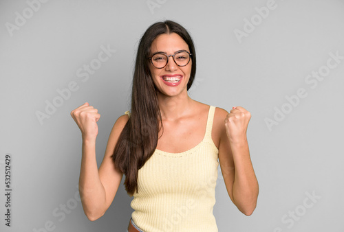 hispanic pretty woman feeling happy, positive and successful, celebrating victory, achievements or good luck