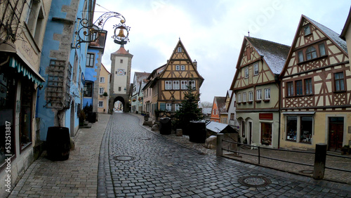 Rothenburg, Germany, December 9, 2021: The Plonlein. A yellow timber-frame house at the entrance of the Spital quarter and the two towers of the old city wall, Siebersturm and Kobolzeller Tor.
