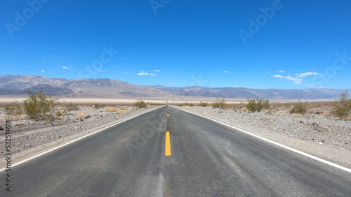State Route 190 crossing Panamint Valley in Death Valley National Park, California, United States. Empty desert road in Death Valley with clear blue sky.