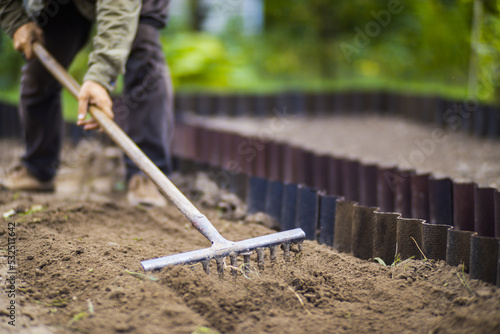 Wallpaper Mural Farmer cultivating land in the garden with hand tools. Soil loosening. Gardening concept. Agricultural work on the plantation Torontodigital.ca