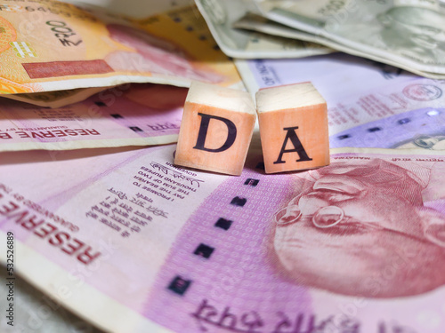Fotografia Concept of DA or Dearness allowance with wooden bids or blocks on indian rupees notes