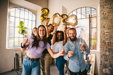 Group of friends at a party celebrate happy new 2023 year with elegant inflatable gold text - People have fun together at home