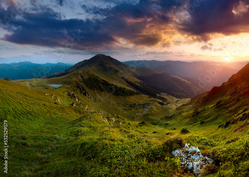 Amazing landscape of mountain valley at sunset. View of dramatic sky and overcast, colorful clouds. Natural summer landscape. Mountain Maramures Nature Park. Carpathians. Romania. Europe.