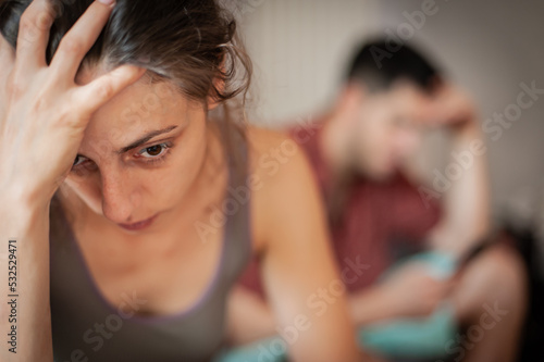 A young sad woman is next to her partner who is texting on the phone with someone, and not paying attention to her.