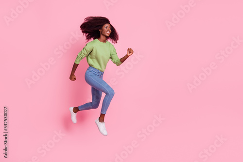 Full length photo of cute pretty lady wear green sweater walking jumping high running empty space isolated pink color background