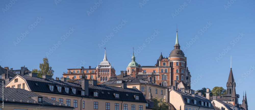 Fototapeta premium Old apartment’s houses at the street Bastugatan, tin roofs, dorms and chimneys in the district Södermalm a sunny autumn day in Stockholm