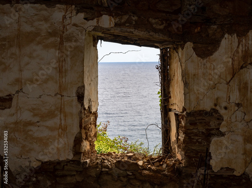 View a t the sea through a window of a ruined house.