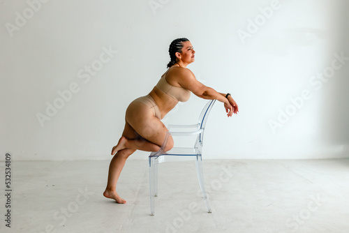 Curvy woman poses with clear chair photo