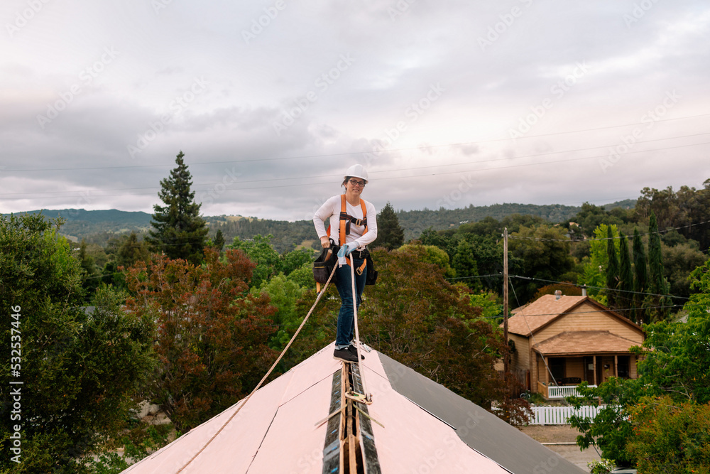 © ByLorena/Stocksy - Woman working on roof with security harness