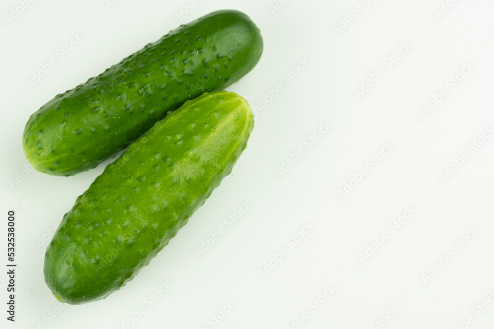 Two cucumbers are abundant on a white background. With a place for the inscription. Close-up. Two cucumbers are abundant on a white background. With a place for the inscription. Close-up.