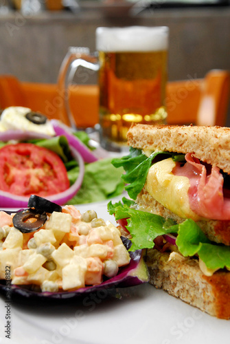 Ham and cheese gratin sandwich, Russian and green salad with cheese, jar of beer, food