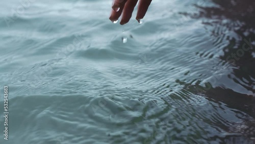 Hands, water and nature with the hand of a woman touching the ocean or sea at the beach. Earth, wellness and relax with the fingers of a female letting h2o flow, drip and drop off of her fingertips