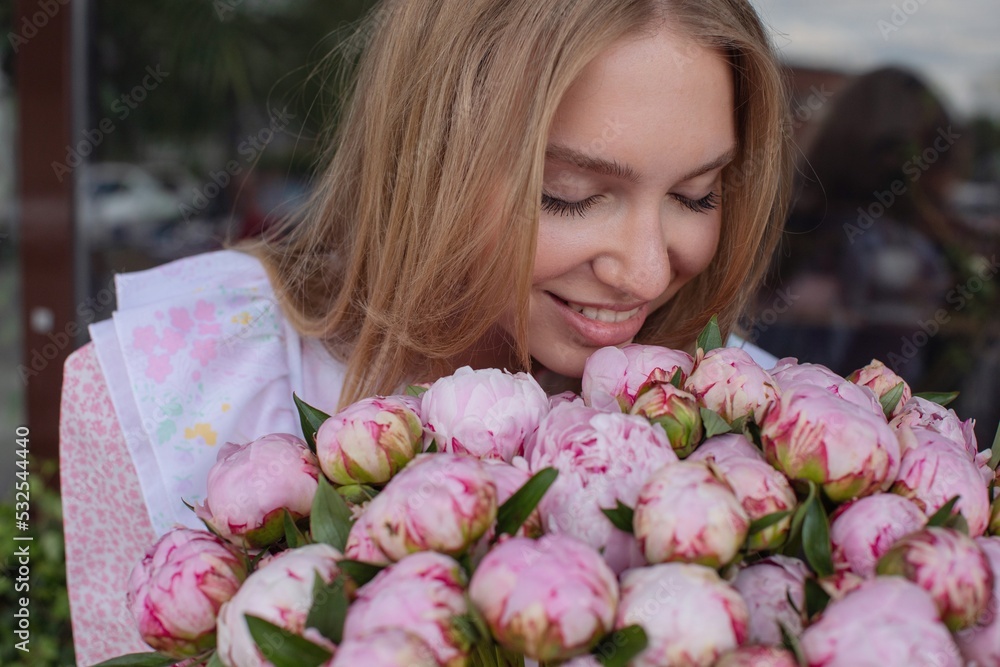 Smiling blond woman smelling flowers Smiling blond woman smelling flowers