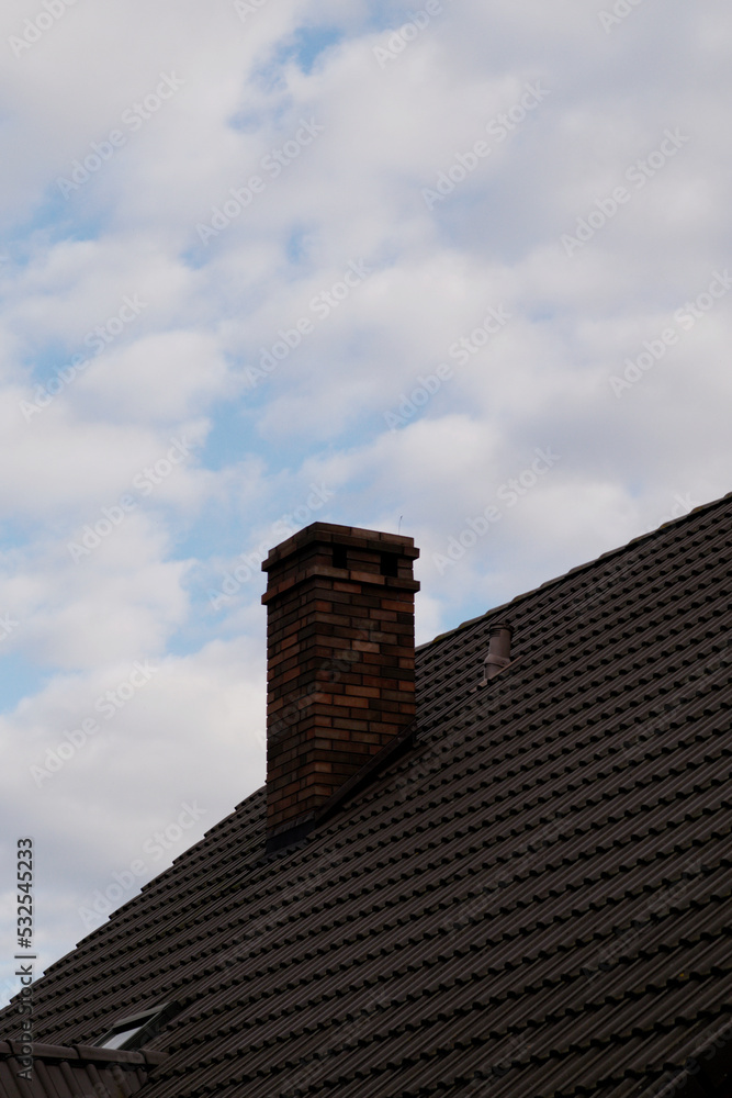 Old red brick chimney on a background of the cloudy sky