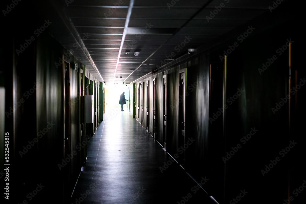 Woman walking alone in the dark. Woman, in a dark, long corridor, defocused Woman walking alone in the dark. Woman, in a dark, long corridor, defocused