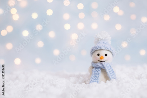 Snowman toy on a Christmas winter background with a copy space. Christmas and New Year greeting card. Snowman in a blue hat.