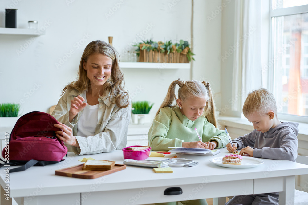 Mother putting lunch for children In Backpack Mother putting lunch for children In Backpack