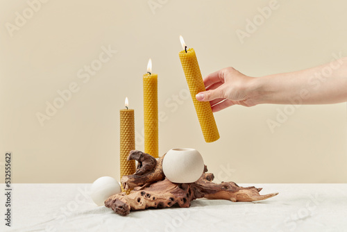 Natural yellow beeswax candles arranged by woman. photo