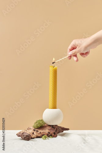 Natural yellow beeswax candle lit by woman.