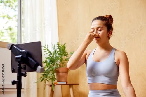 Young woman practicing Pranayama during online lesson