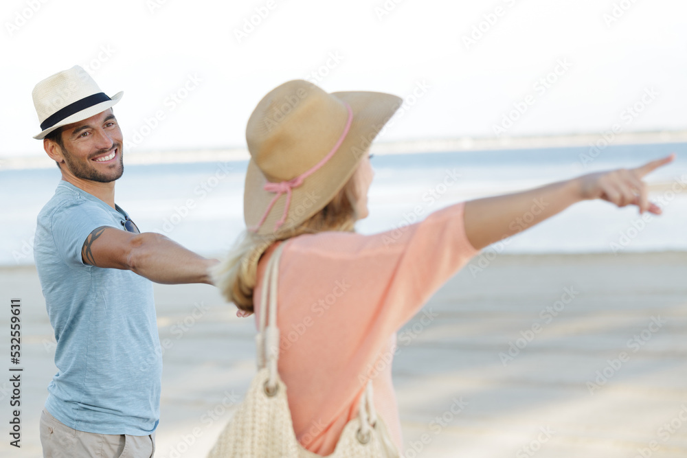 couple on the beach pointing into the distance