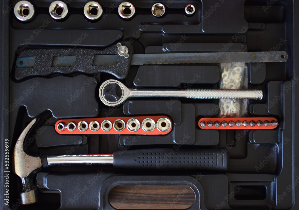 Vista superior de herramientas de trabajo usadas, copas, maneral, sierra, martillo y puntas para destornillador.