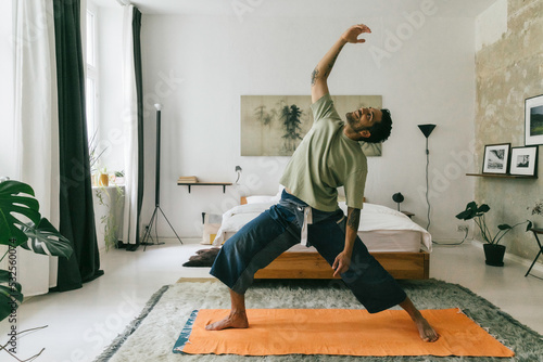 Young Man Doing Yoga in Bright White Bedroom photo