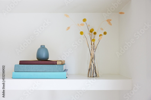 Books, vase and flowers on shelf in home