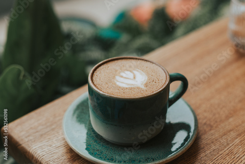 Delicious cappuccino on alternative milk in a green ceramic mug on a wooden table. Beautiful double cappuccino serve. Hot coffee for breakfast