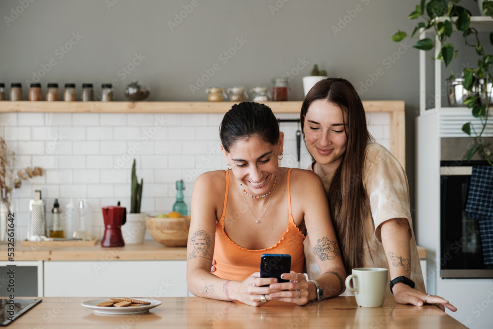 © Malquerida Studio/Stocksy - Couple using mobile phone in the kitchen © Malquerida Studio/Stocksy - Couple using mobile phone in the kitchen