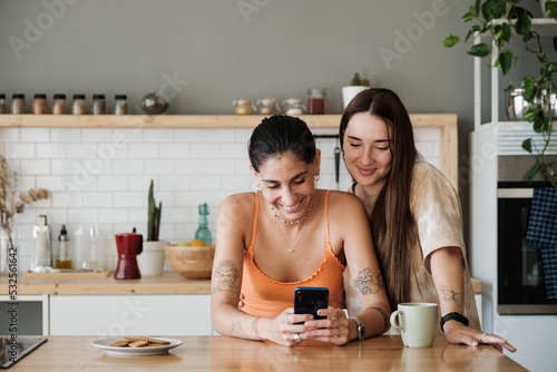 Couple using mobile phone in the kitchen photo