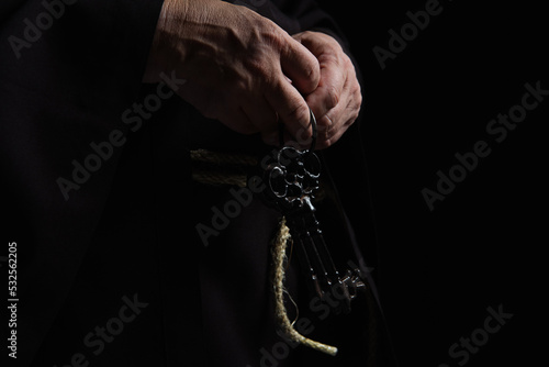 partial view of medieval abbot with keys isolated on black.