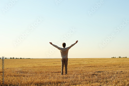 Young man with raised hands in the autumn meadow on a blue clean sky background. Pavel Kubarkov, landscape with blue sky, meadow and i. Photo was taken 10 September 2022 year, MSK time in Russia.
