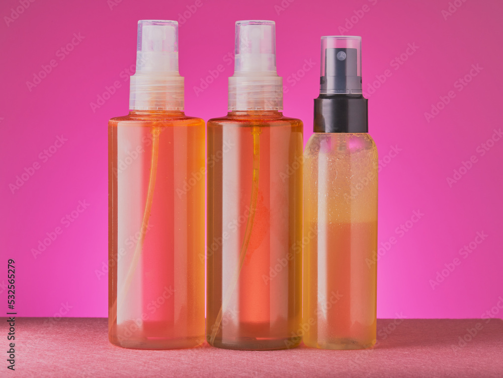 Set of cosmetic dispensers on a pink gradient background.
