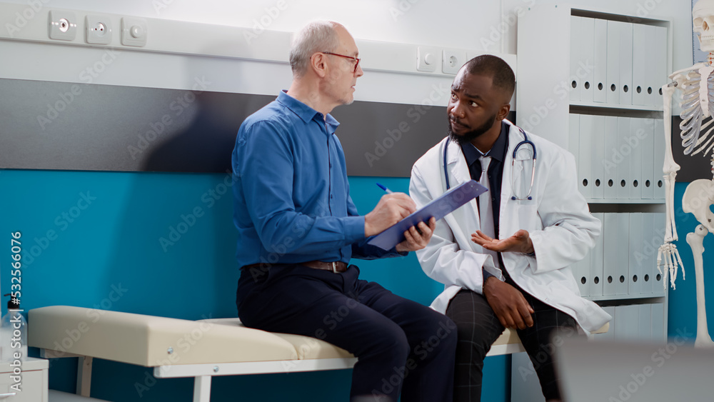 Obraz premium Elderly patient signing consultation form to receive medication and prescription treatment. Physician helping old man with disease to cure diagnosis at examination appointment.