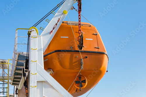 Orange lifeboat hanging on the side of a ferry