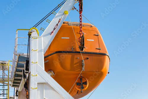 Orange lifeboat hanging on the side of a ferry photo