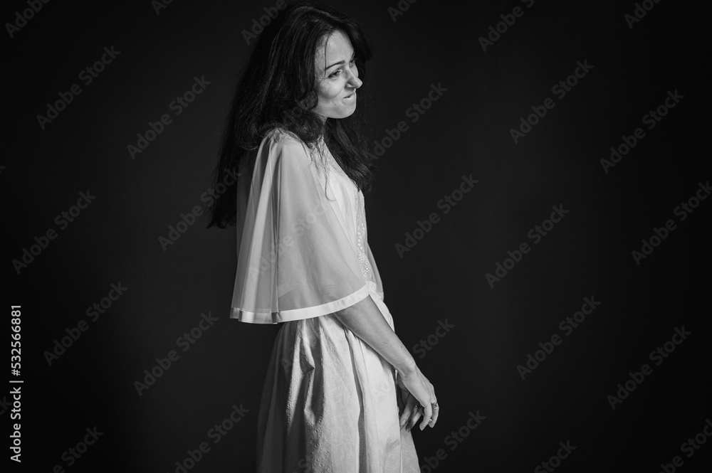 Black and white classic photo. Emotional young girl smiling with skeptical and suspicious emotions, thoughtful and pensive. Portrait of a sarcastic woman on a gray background. Selective focus