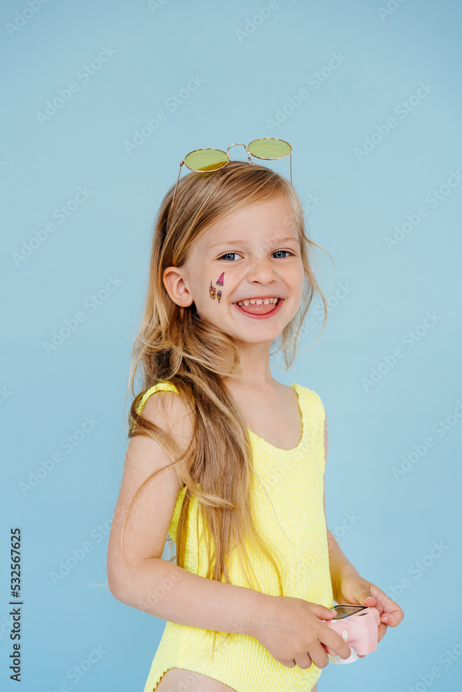 Smiling child in swimsuit with sticker on face holding camera Smiling child in swimsuit with sticker on face holding camera