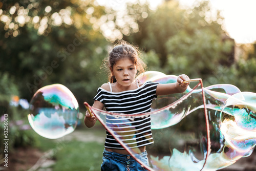 Young girl is creating giant soap bubbles. photo