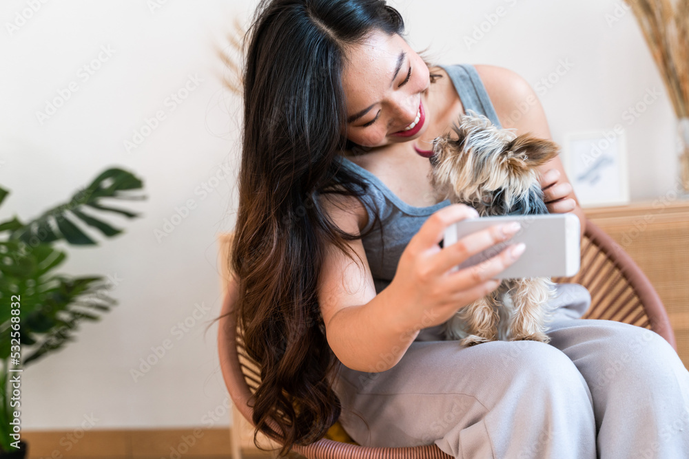 Woman taking a selfie with her little dog at home.