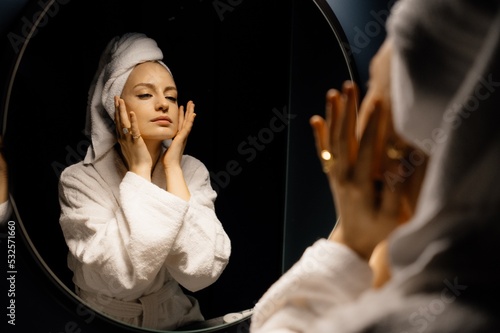 Young woman touching face near mirror
