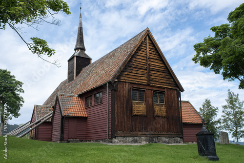 Kvernes, Norway - July 03, 2022: Kvernes Stave Church is a former parish church of the Church of Norway in Averoy Municipality in More og Romsdal county. Cloudy summer day. Selective focus photo