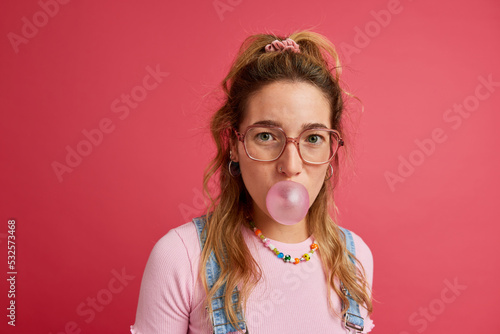 Teenage lady blowing bubble gum in studio photo