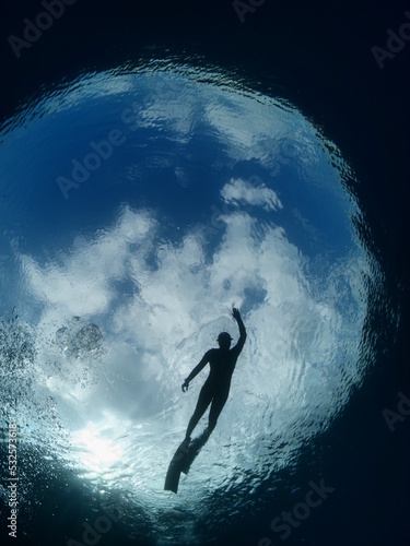 free diver swimming underwater silhouette  clouds and sky view earth photo