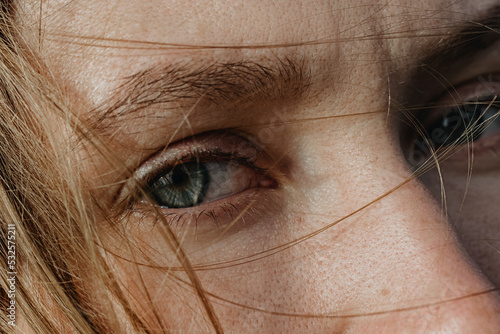 Close Up woman's portrait with grey eyes and blonde hair covered face 