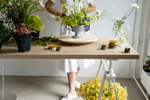 anonymous woman standing behind table with flowers photo