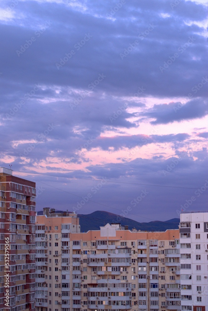 Pink sunset, amazing clouds floating across the sky, panoramic view of urban new buildings, banner, screensaver.