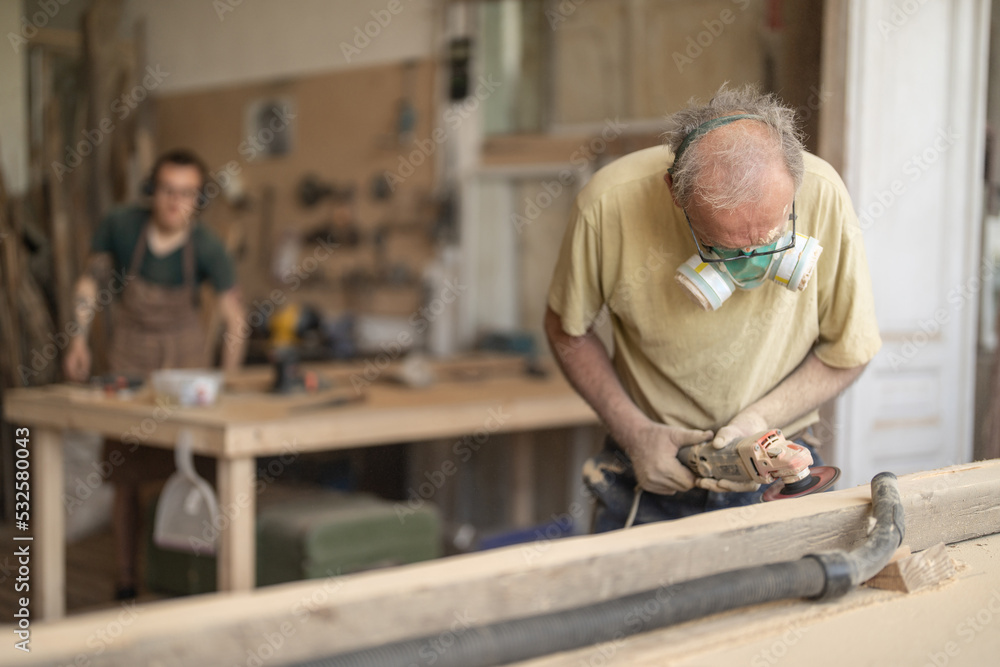 Senior man using grinder removes old paint from furniture Senior man using grinder removes old paint from furniture