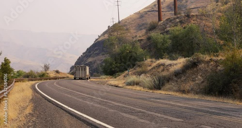 Pickup truck towing stock trailer travels winding road through Hells Canyon along the Snake River marking the border between Oregon and Idaho- Low angle